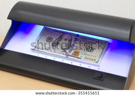 Examining a new Dollar Banknote with a Money Detector