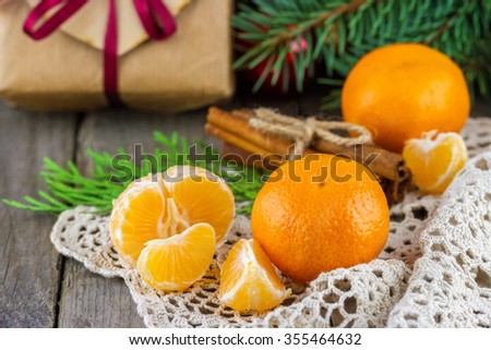 Christmas (New Year) composition. Tangerines, acorns, cinnamon sticks decorated twine bow, gift box, fur-tree branches on wooden background
