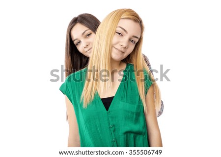 Two smiling attractive teenage girls - blonde and brunette-posing  on white background