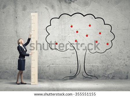 Young businesswoman in suit measuring tree with ruler