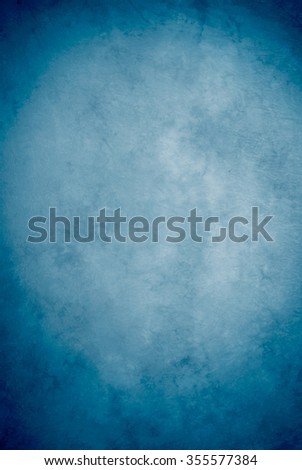 Traditional painted canvas or muslin fabric cloth studio backdrop or background, suitable for use with portraits, products and concepts. Shade of blue, lighter in the center, darker on edges. Royalty-Free Stock Photo #355577384