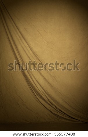 Traditional canvas or muslin fabric cloth studio backdrop or background, suitable for use with portraits, products and concepts. Tan or brown color. Royalty-Free Stock Photo #355577408