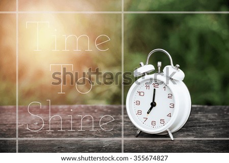 quote time to shine on image vintage alarm clock on table with blur green background and sunray