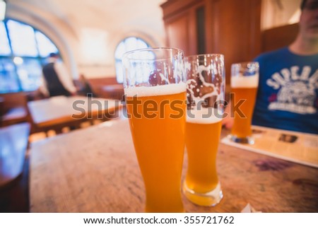 Beautiful vibrant picture of gold coloured beer glasses assortment, on wooden table, a summer sunny day, german unfiltered wheat beer