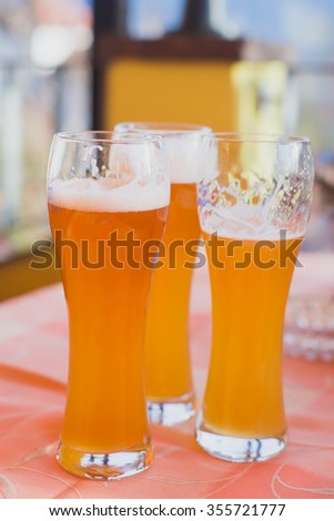 Beautiful vibrant picture of gold coloured beer glasses assortment, on wooden table, a summer sunny day, german unfiltered wheat beer