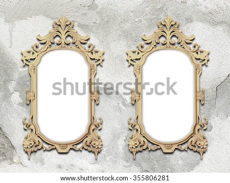 Close-up of two golden baroque picture frames on weathered concrete wall background