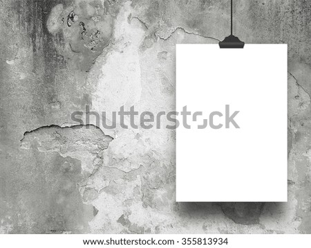 Close-up of one hanged paper sheet frame with clip on weathered concrete wall background