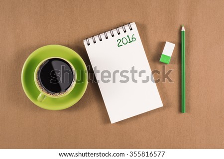 Top view office desk mockup: notebook and coffee cup brown wooden background. New year 2016 resolution