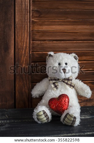 Toy bear and red heart on a dark wooden surface. Valentine's day gift. Holiday background