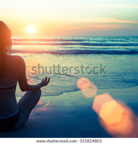 Caucasian woman practicing yoga at seashore during sunset.