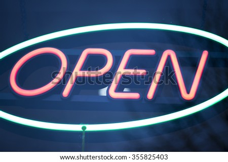 Neon shop open store sign at night in street photograph.