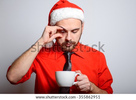 Winter, a business man holding a cup of coffee or tea. Corporate party, Christmas hat isolated portrait of a man on a gray background, studio photo.