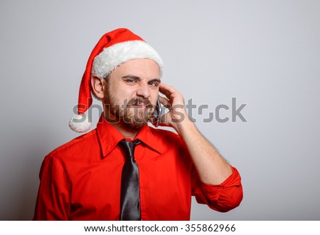 Winter, a business man on the phone says in exasperation. Corporate party, Christmas hat isolated portrait of a man on a gray background, studio photo.