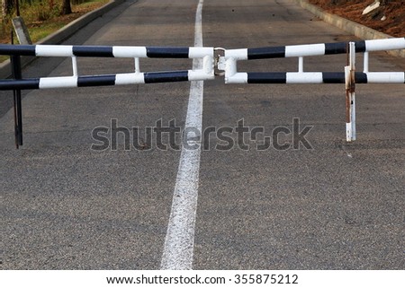 Closed striped road barrier on the way at evening