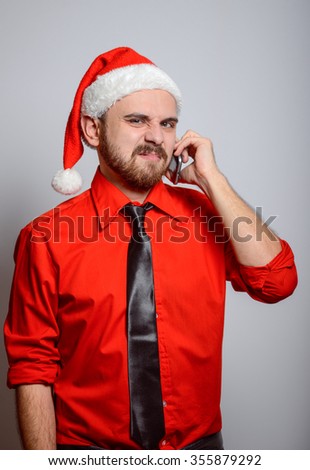 Winter, a business man on the phone says in exasperation. Corporate party, Christmas hat isolated portrait of a man on a gray background, studio photo.