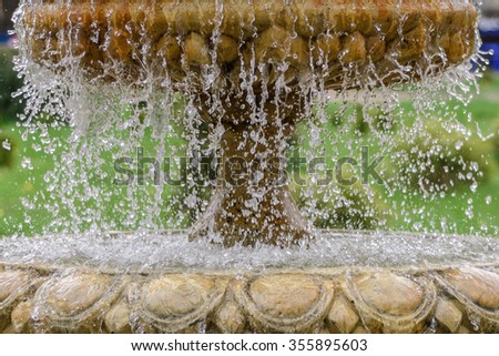 An old vintage fountain with lots drops and splashes and a green background