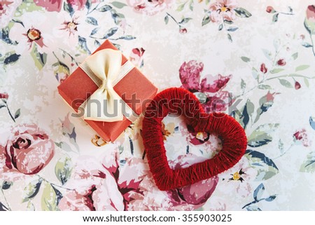 simple surprise little box with bow and red heart on stylish flower paper, holiday celebration concept