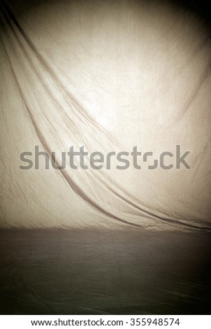 Painted canvas or muslin fabric cloth studio backdrop or background, suitable for use with portraits, products and concepts. Tan color with center spot lighting. Royalty-Free Stock Photo #355948574
