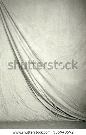 Draped canvas or muslin fabric cloth studio backdrop or background, suitable for use with portraits, products and concepts. Light gray color. Royalty-Free Stock Photo #355948592