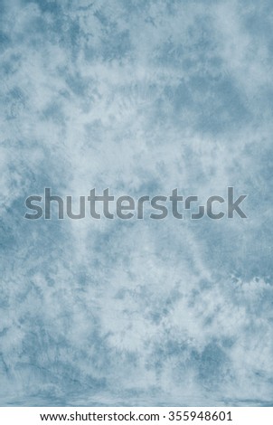 Painted canvas or muslin fabric cloth studio backdrop or background, suitable for use with portraits, products and concepts. Light blue painted design. Royalty-Free Stock Photo #355948601