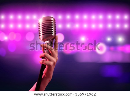 Close up of female hand on blurred background holding microphone 