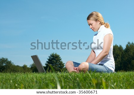 The girl with laptop on a green lawn