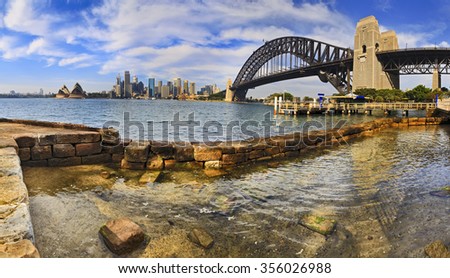 rock pool in Sydney harbour in a foreground of CBD view across water with skyscrapers and Bridge's arch in panoramic layout Royalty-Free Stock Photo #356026988