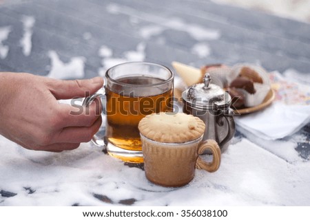 Red frozen male hand holding a tea cup, outdoor shot with shallow depth of field