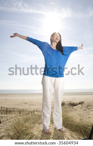 Mid adult woman standing with her arms open on the beach