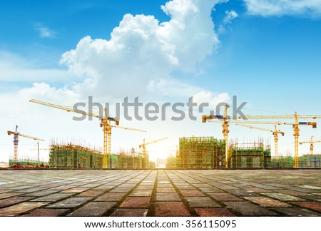 Crane and building construction site against blue sky Royalty-Free Stock Photo #356115095