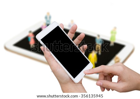 woman hand hold mobile over blurred image of group of micro people cartoon (people model) standing,sitting on cell phone/smart phone/telephone/tablet ; business connection by technology concept
