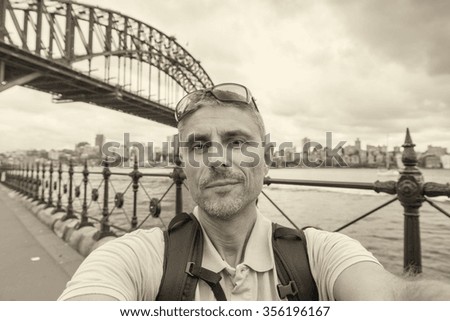 Happy man making selfie in Sydney with Harbour Bridge on background.