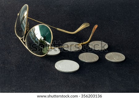 Coins and sunglasses in black carpet