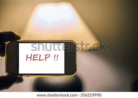 Photo with mobile phone in the hands of a man with the word help screen and background of a lamp