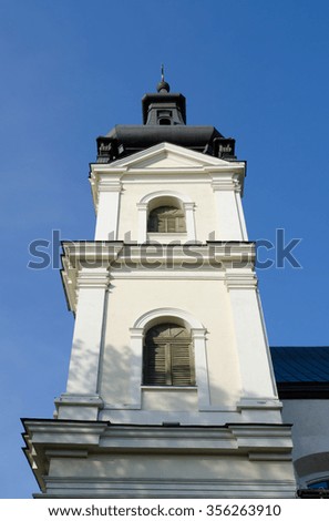 Tower of the Church of St. Michael the Archangel with arched windows, closed shutters on the background of blue sky. Side view. Lvov, Ukraine