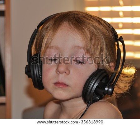Child listens to music in headphones at bright spring evening