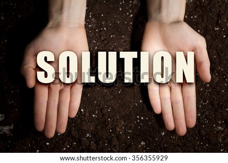 Male hands on soil background showing in palms idea word solution