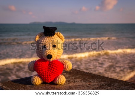 Teddy Bear with red heart sitting near the beach - vintage tone
