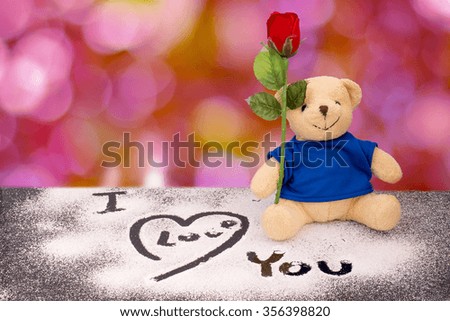 Teddy bear sitting hold plastic rose and i love you text on glass floor with bokeh background,  Valentine background