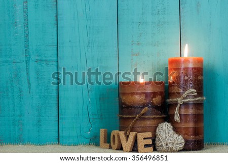 Valentine's Day spa composition with textured candles, rope heart and the word LOVE by antique rustic teal blue wood background;  Mothers Day and love concept background with painted copy space