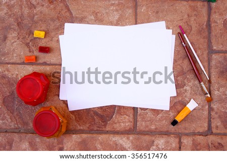 Mock-up for presentations with seashell, roses, watercolor, pencils. Desktop workplace designer, artist, painter top view. Modern template for advertising, product on a brick background, blank paper
