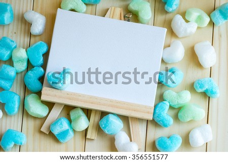 Blank drawing frame and blue green heart surrounded, flat lay.