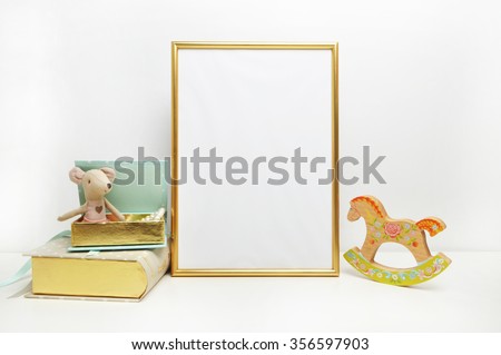 Gold frame mock-up, and white wall with toys.mouse, and mint book
Place work