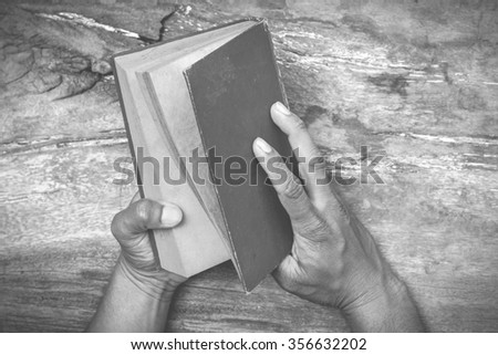 hands holding the old book on old wooden table