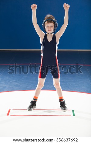 Male youth wrestler with arms up in victory