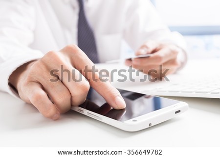 Closeup of man's hands holding credit cards and using mobile phone. Concept for m-commerce, online shopping, m-banking, internet security.