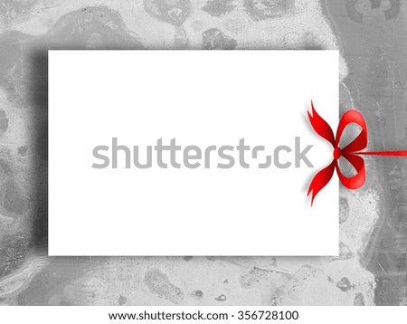 Close-up of one hanged paper sheet frame with red ribbon on weathered concrete wall background