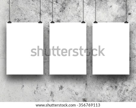 Close-up of three hanged paper sheet frames with clips on weathered concrete wall background