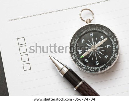 Concept : pen and compass on book with checklist box, wood background