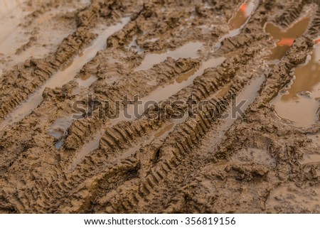 Texture of wet brown mud with bicycle tyre tracks